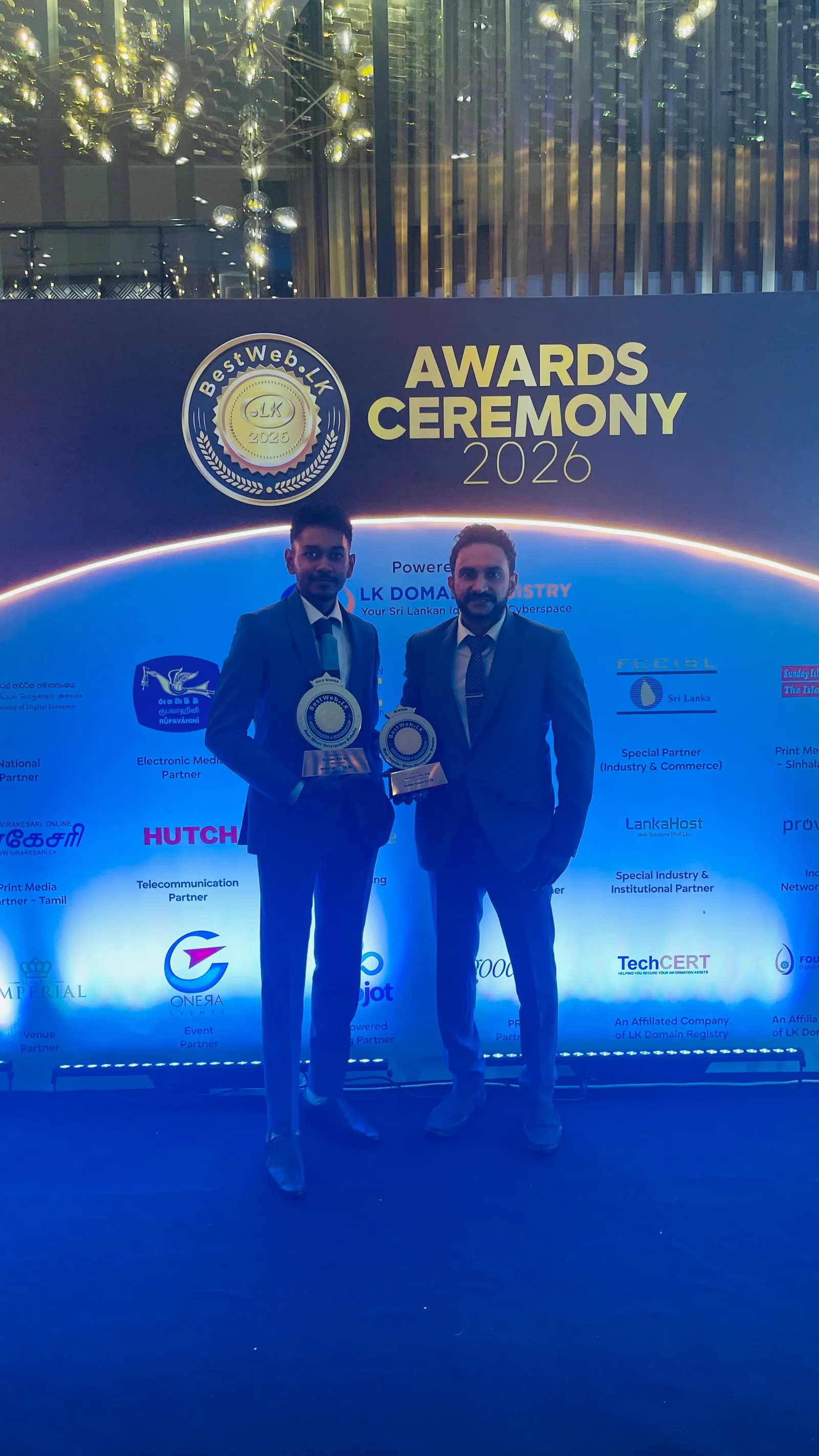 Two members of the Zonova team with the Gold Winner and Most Popular Website trophies at the BestWeb.lk 2026 ceremony in Colombo.