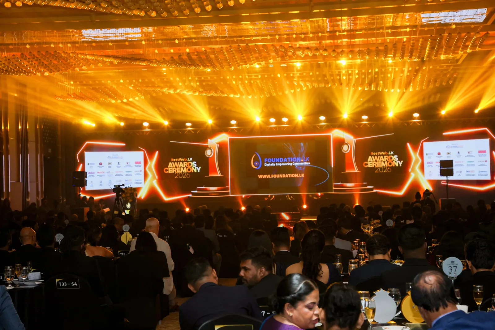 The BestWeb.lk 2026 ceremony in Colombo: a full banquet hall under stage lighting, with the ceremony screens above the stage.