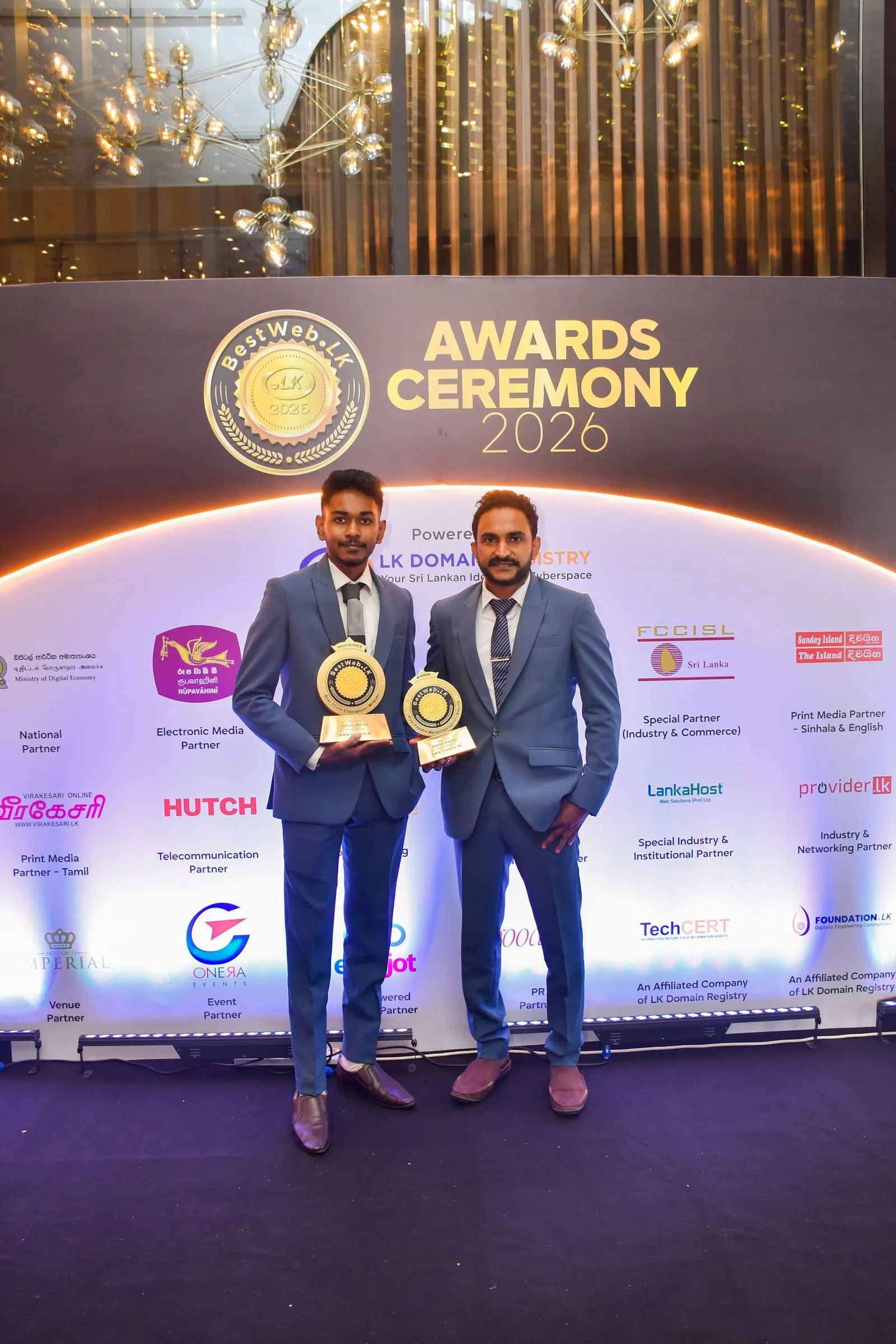 Two of the Zonova team holding both trophies in front of the Awards Ceremony 2026 backdrop.